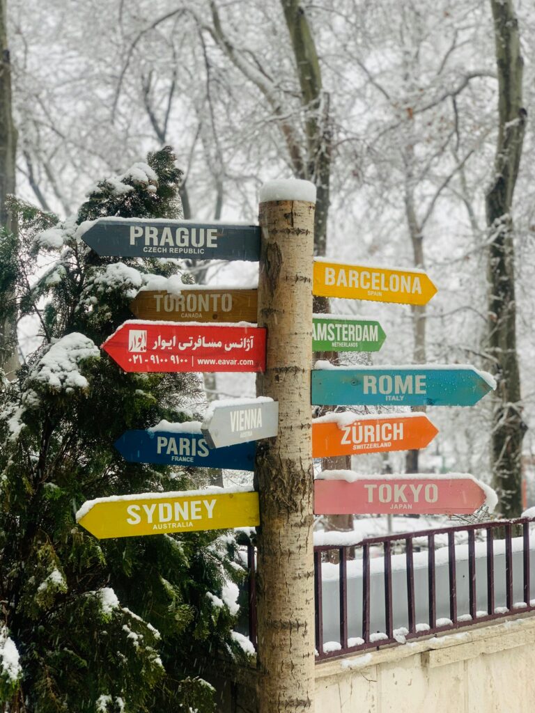 pexels-photo-3600096-3600096 Colorful signpost displaying international city names against a snowy background.